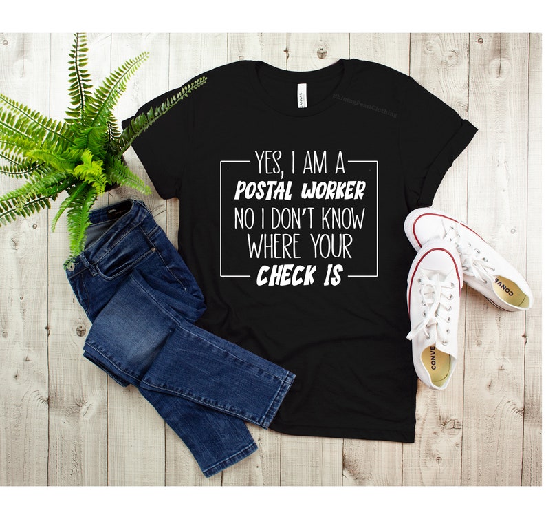 May include: Black t-shirt with white text that reads "YES, I AM A POSTAL WORKER NO I DON'T KNOW WHERE YOUR CHECK IS".