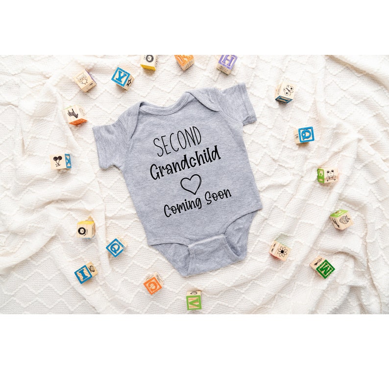 May include: A gray onesie with the text "Second Grandchild Coming Soon" and a heart symbol.