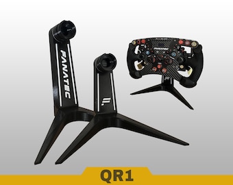 May include: Two black display stands with white Fanatec branding and a racing steering wheel mounted on a third stand. The stands feature a tripod-style base and a cylindrical top mount. The text QR1 is displayed in a yellow banner at the bottom.