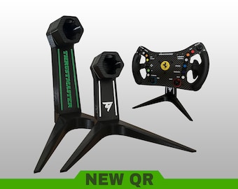 May include: Two black 3D-printed stands for gaming steering wheels, one tall with green Thrustmaster text and one shorter with a white TM logo. A black Ferrari-branded racing wheel is mounted on a separate stand, featuring colorful buttons.