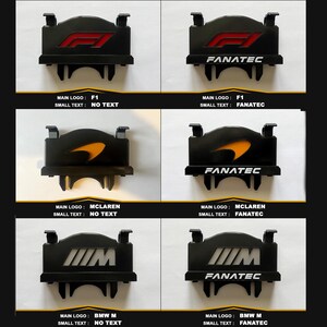Op de afbeelding: Een collectie van zes zwarte rechthoekige displaycovers voor stuurwielen met diverse logo's zoals F1, McLaren en BMW M. Sommige versies bevatten de witte tekst FANATEC aan de onderkant, terwijl andere geen extra tekst onder het hoofdlogo hebben.