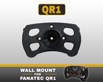 May include: A black wall mount for a Fanatec QR1 racing wheel quick release system. The mount features a central circular hub with four surrounding cutouts and mounting holes. Text at the top reads QR1, and text at the bottom reads WALL MOUNT FOR FANATEC QR1, accompanied by a small image of a steering wheel.