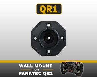May include: A black octagonal wall mount for a Fanatec QR1 racing wheel quick release system. The mount features four circular screw holes and a central circular opening. Text above reads QR1, and text below reads WALL MOUNT FOR FANATEC QR1.