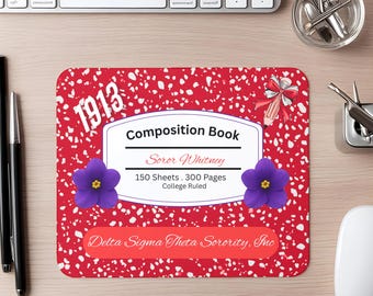 May include: A rectangular mouse pad with a red and white speckled pattern. It features the text 1913, Composition Book, Soror Whitney, 150 Sheets, 300 Pages, College Ruled, and Delta Sigma Theta Sorority, Inc. Two purple flowers and a pencil are shown.