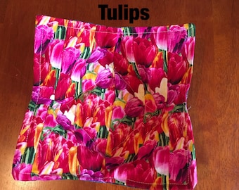May include: A pink and yellow floral print hot pad with the word "Tulips" printed in black.