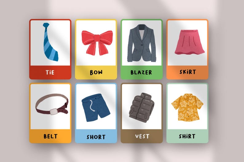 May include: A set of eight educational flashcards featuring illustrations of clothing items including a blue tie, red bow, gray blazer, pink skirt, brown belt, blue shorts, gray vest, and a yellow floral shirt with the text labels below each.