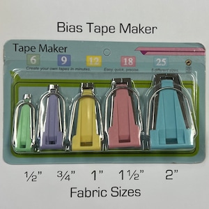 Può includere: Un set di cinque strumenti per creare nastri di sbieco in diversi colori e dimensioni. Gli strumenti sono etichettati con le dimensioni del tessuto che creano: 1/2 pollice, 3/4 pollice, 1 pollice, 1 1/2 pollici e 2 pollici. La confezione riporta anche "Tape Maker" e "Bias Tape Maker".