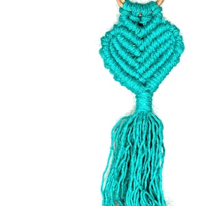May include: A teal blue macrame keychain with a wooden ring and a tassel.