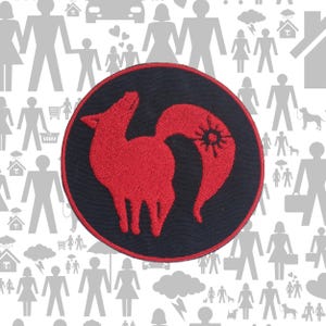 Pode incluir: Um emblema bordado circular com fundo preto, borda vermelha e uma silhueta estilizada de raposa vermelha no centro. O design da raposa inclui um s&iacute;mbolo semelhante a um sol na cauda, feito com um bordado detalhado em fio vermelho.