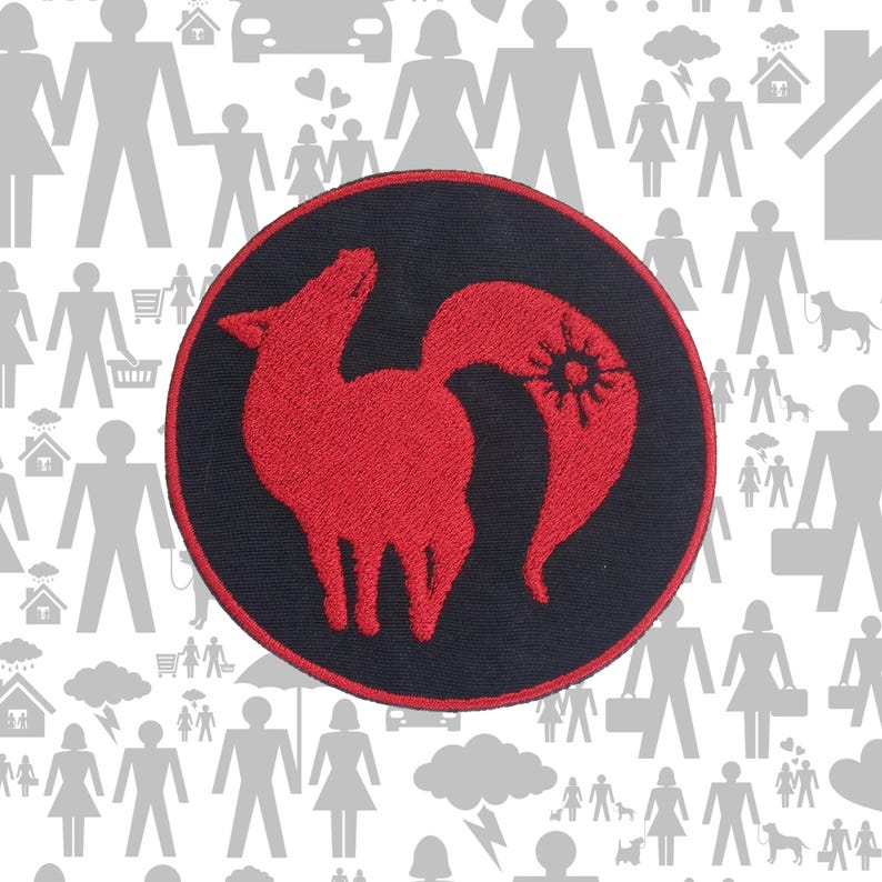 Pode incluir: Um emblema bordado circular com fundo preto, borda vermelha e uma silhueta estilizada de raposa vermelha no centro. O design da raposa inclui um s&iacute;mbolo semelhante a um sol na cauda, feito com um bordado detalhado em fio vermelho.