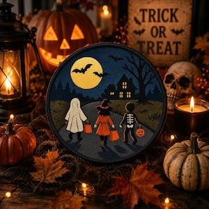 Può includere: Una toppa ricamata circolare che raffigura una scena di Halloween con tre bambini in costume che camminano verso una casa sotto una grande luna gialla. Il disegno include un fantasma, una strega e uno scheletro, tutti con sacchetti arancioni.