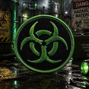 May include: A circular embroidered patch featuring a bright green biohazard symbol centered on a black background with a matching green stitched border. The design is clean and clearly defined, showcasing the iconic three-bladed hazard emblem.