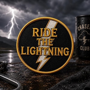 May include: A circular embroidered patch with a black background and a gold border. The text RIDE THE LIGHTNING is stitched in gold thread, overlaid with a white lightning bolt graphic. The patch features a textured fabric finish throughout.