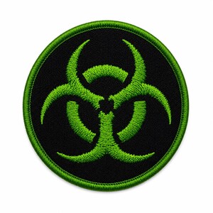 May include: A circular embroidered patch featuring a bright lime green biohazard symbol centered on a solid black background. The patch has a thick, stitched lime green border that frames the circular design with a textured thread finish.