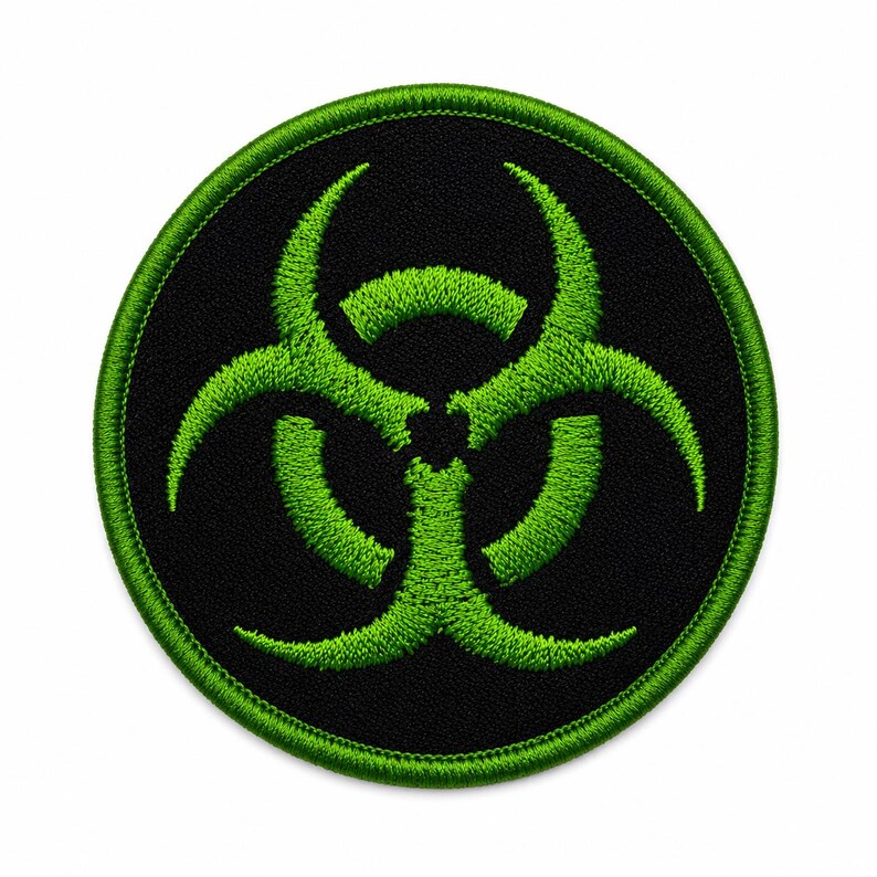 May include: A circular embroidered patch featuring a bright lime green biohazard symbol centered on a solid black background. The patch has a thick, stitched lime green border that frames the circular design with a textured thread finish.