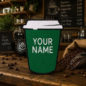 May include: A dark green embroidered patch shaped like a coffee cup with a white lid. The center of the patch features the white embroidered text "YOUR NAME" in a clean, sans-serif font. The patch has a black border and a textured fabric finish.