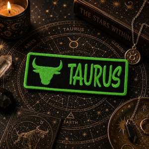 May include: A rectangular embroidered patch featuring a black background with a bright green border. The patch displays a green bull head silhouette on the left and the word TAURUS in green capital letters on the right side.