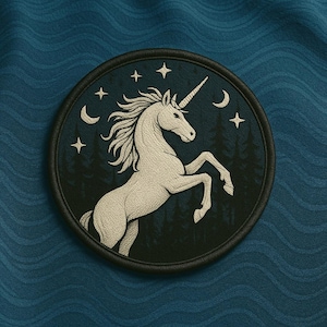 May include: Embroidered patch featuring a white unicorn rearing up against a dark blue background with stars, crescent moons, and a forest silhouette. The patch has a black border and is set against a blue fabric.