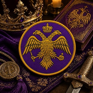 Può includere: Una toppa rotonda viola con un disegno di aquila bicipite dorata, una corona e un bordo dorato. La toppa è circondata da una corona dorata, un libro con un'aquila dorata, una spada e un ciondolo con una croce.