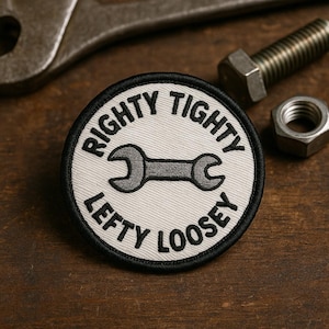 May include: A round patch with the text "Righty Tighty, Lefty Loosey" encircling a gray wrench graphic. The patch has a white background with a black border. A wrench, bolt, and nut are in the background.