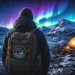 May include: A circular embroidered patch featuring a vibrant depiction of the aurora borealis over snow-capped mountains and icy waters. The patch has a yellow border and is attached to the back of a dark olive green canvas backpack with straps.