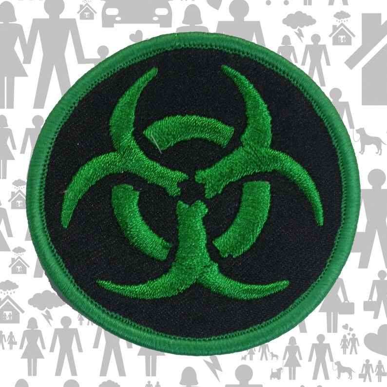 May include: A circular embroidered patch featuring a black background with a vibrant green biohazard symbol centered on the fabric. The patch is finished with a matching green stitched border that frames the circular design clearly.