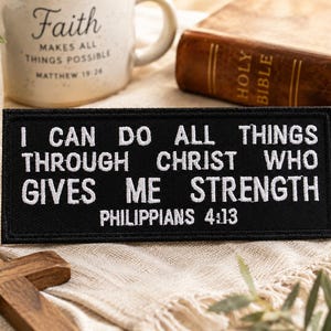 以下が含まれることがあります： 「I CAN DO ALL THINGS THROUGH CHRIST WHO GIVES ME STRENGTH PHILIPPIANS 4:13」の文字が刺繍された黒いパッチ。背景には「Faith」の文字が入ったセラミックマグと聖書があります。