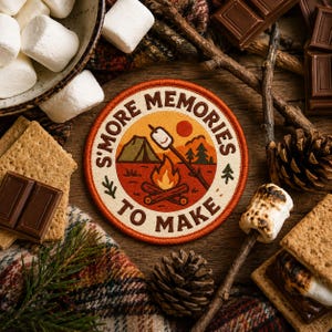 Op de afbeelding: Een ronde patch met de tekst "S'MORE MEMORIES TO MAKE" omringt een kampeerscène met een kampvuur, tent en marshmallow op een stok. De afbeelding bevat marshmallows, graham crackers, chocoladerepen en een geruite deken.