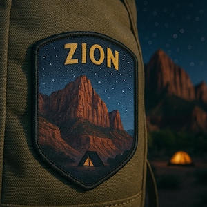 May include: A patch with the word "ZION" in gold lettering, featuring a landscape of red rock mountains under a starry night sky. A tent is visible at the base of the mountains. The patch is sewn onto a green backpack.