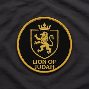 Puede incluir: Parche bordado circular negro con un león dorado, corona y escudo. El texto "LION OF JUDAH" es dorado. Borde dorado. Diseño heráldico.