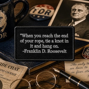 May include: A rectangular black patch featuring white embroidered text that reads: When you reach the end of your rope, tie a knot in it and hang on. -Franklin D. Roosevelt. The patch has a stitched border and a flat, fabric-like texture.