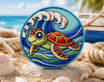 Op de afbeelding: Ronde geborduurde patch met een cartoon zeeschildpad die voor een golf zwemt. De schildpad heeft een gele kop, een oranje schild en een groen lichaam. De patch is omgeven door een blauwe rand en staat op een zandstrand.