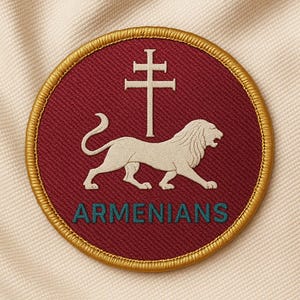 Può includere: Toppa ricamata circolare con sfondo bordeaux, raffigurante un leone bianco e una croce a doppia barra. Il testo "ARMENIANS" è turchese. La toppa ha un bordo dorato ed è posta su un tessuto color crema.