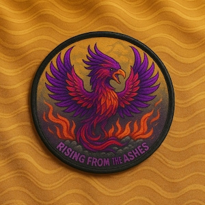 May include: Round patch featuring a phoenix design in shades of purple, red, and orange, with a black border. The phoenix is rising from flames, and the text "RISING FROM THE ASHES" is arched below the bird. The background is a textured gold color.