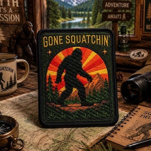 Puede incluir: Un parche rectangular bordado que presenta la silueta negra de una criatura Bigfoot caminando a través de un bosque. El fondo muestra un diseño de rayos de sol naranja y amarillo vibrante detrás de una cordillera. El texto GONE SQUATCHIN' está bordado en amarillo en la parte superior.