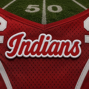 May include: A red mesh athletic jersey featuring the word Indians embroidered in red script with a white outline across the chest. The garment includes white trim details and partial white numbers visible on the sides of the V-neck collar area.