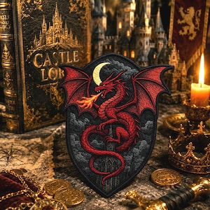 May include: Embroidered patch featuring a red dragon breathing fire, set against a black shield with a crescent moon. The patch is surrounded by a medieval theme, including a book with "Castle Lore" text, coins, and a candle.