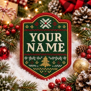 Peut inclure: Un écusson brodé en forme de bouclier avec un fond vert foncé et une bordure rouge. L'écusson affiche le texte YOUR NAME en lettres couleur crème, entouré d'un motif festif de style tricot en rouge, blanc et doré.