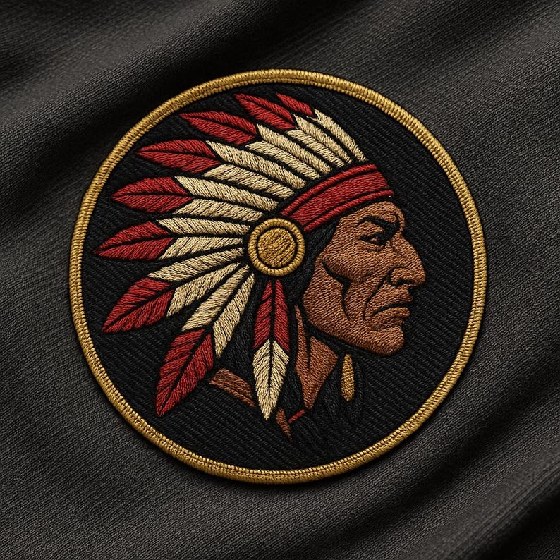 K&ouml;nnte beinhalten: Runder, gestickter Aufn&auml;her mit einem indianischen H&auml;uptling im Profil, der einen Federkopfschmuck tr&auml;gt. Der Aufn&auml;her hat einen schwarzen Hintergrund und einen goldenen Rand. Das Gesicht des H&auml;uptlings ist braun, die Federn sind rot und beige.