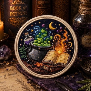 May include: A circular embroidered patch featuring a black cauldron with bubbling green liquid, a glowing open book, a crescent moon, and stars against a dark background. The patch has a thick, light-colored stitched border around the edge.