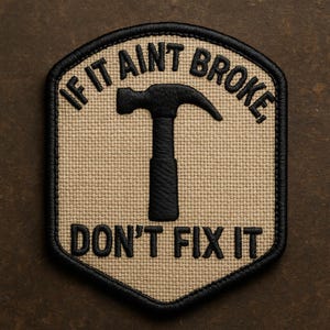 Peut inclure: Écusson beige avec texte brodé noir et un marteau. Le texte dit « IF IT AINT BROKE, DON'T FIX IT ». L'écusson a une bordure noire et un aspect texturé, adapté à un mécanicien ou bricoleur.