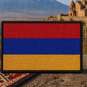 May include: A rectangular patch featuring the Armenian flag, with horizontal stripes of red, blue, and yellow. The patch is set against a backdrop of a carved wooden vessel, pomegranates, and a mountain landscape.