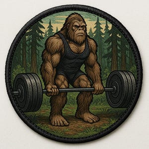 May include: A circular patch depicting a brown Bigfoot lifting a barbell in a forest. The Bigfoot is clad in a black vest and shorts. The patch has a black stitched edge, with a backdrop of green grass and trees.