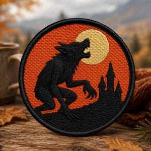 May include: A circular embroidered patch featuring a black werewolf silhouette howling at a large yellow moon against a textured orange background. The design includes a black castle silhouette on a hill, all enclosed by a thick black stitched border.
