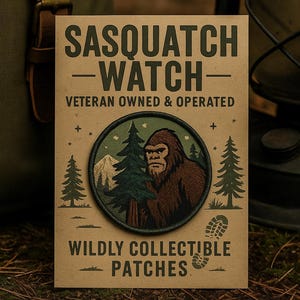 May include: A rectangular patch with the text "SASQUATCH WATCH" and "WILDLY COLLECTIBLE PATCHES". The patch features a circular design with a brown Bigfoot illustration, trees, and a mountain scene. The patch is on a brown background.