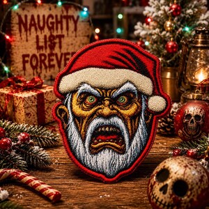 Puede incluir: Un parche bordado que muestra un rostro de Papá Noel estilizado y agresivo con gorro rojo, barba blanca y ojos verdes intensos. El diseño incluye costuras detalladas en tonos rojos, blancos, amarillos y negros, capturando una expresión feroz.