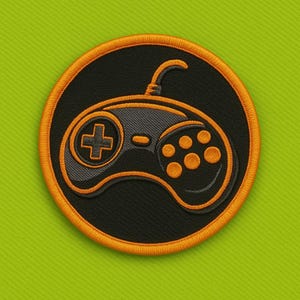 May include: Embroidered patch featuring a black and orange video game controller design. The controller is centered on a black circle with an orange border. The patch has a retro gaming theme and is set against a green background.