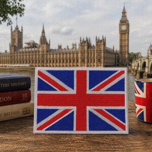 May include: A rectangular patch featuring the Union Jack flag, with red and white stripes on a blue background. A mug with the same flag design is also visible. The background shows the Houses of Parliament and Big Ben.