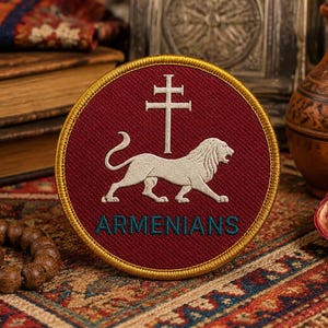 May include: A round maroon patch with a gold border features a white lion and a cross symbol. The text "ARMENIANS" is in teal. The patch is on a patterned rug, with books and a pomegranate nearby.