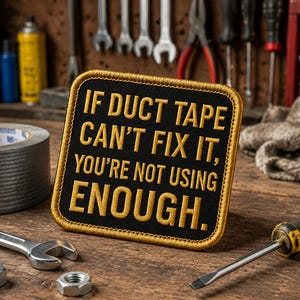 May include: A black patch with gold stitching and the text "IF DUCT TAPE CAN'T FIX IT, YOU'RE NOT USING ENOUGH." A roll of gray duct tape, a spanner, nuts, and a screwdriver are on a wooden surface.